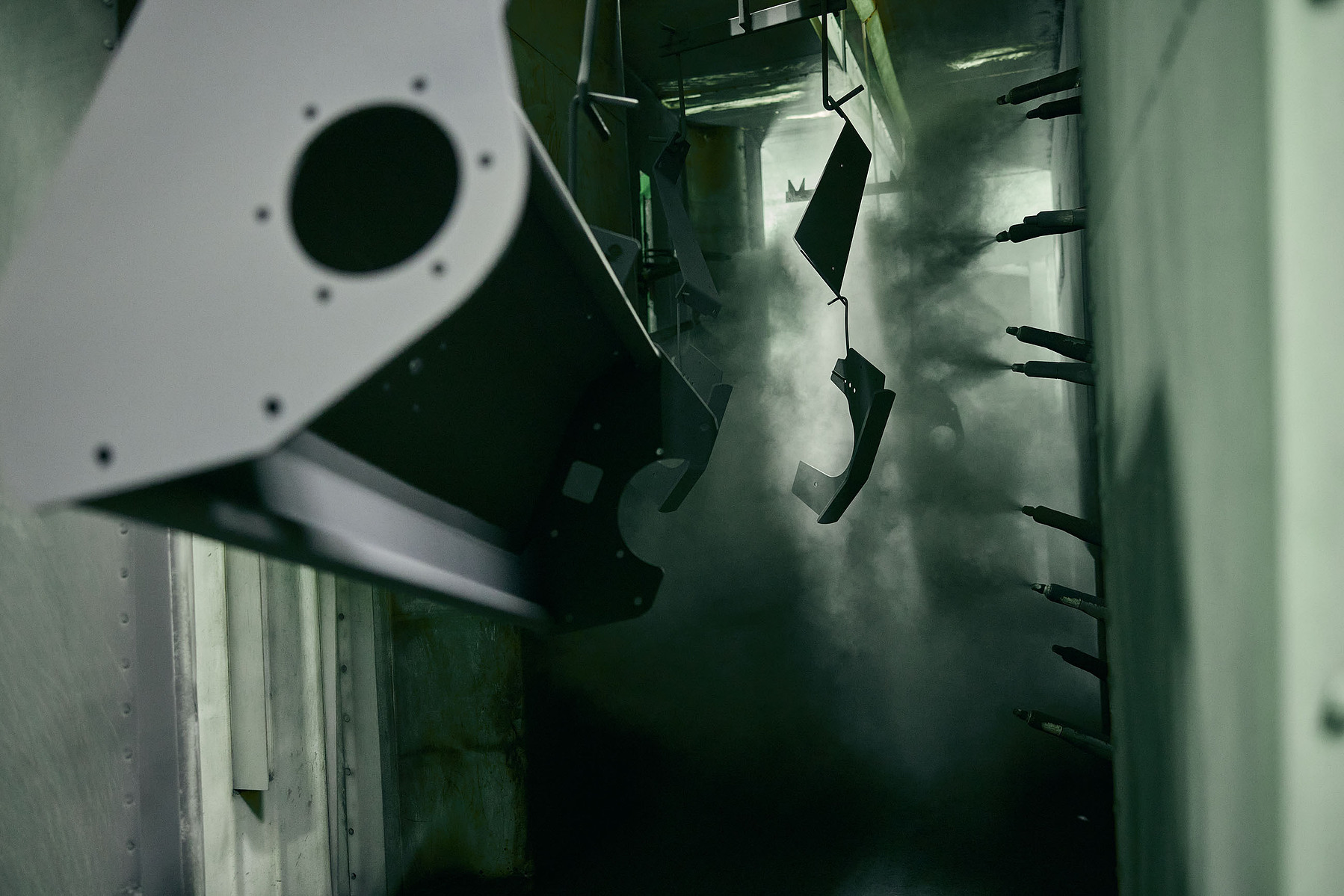 Close-up view of a dark industrial machine with curved metal tooling and cylindrical components.