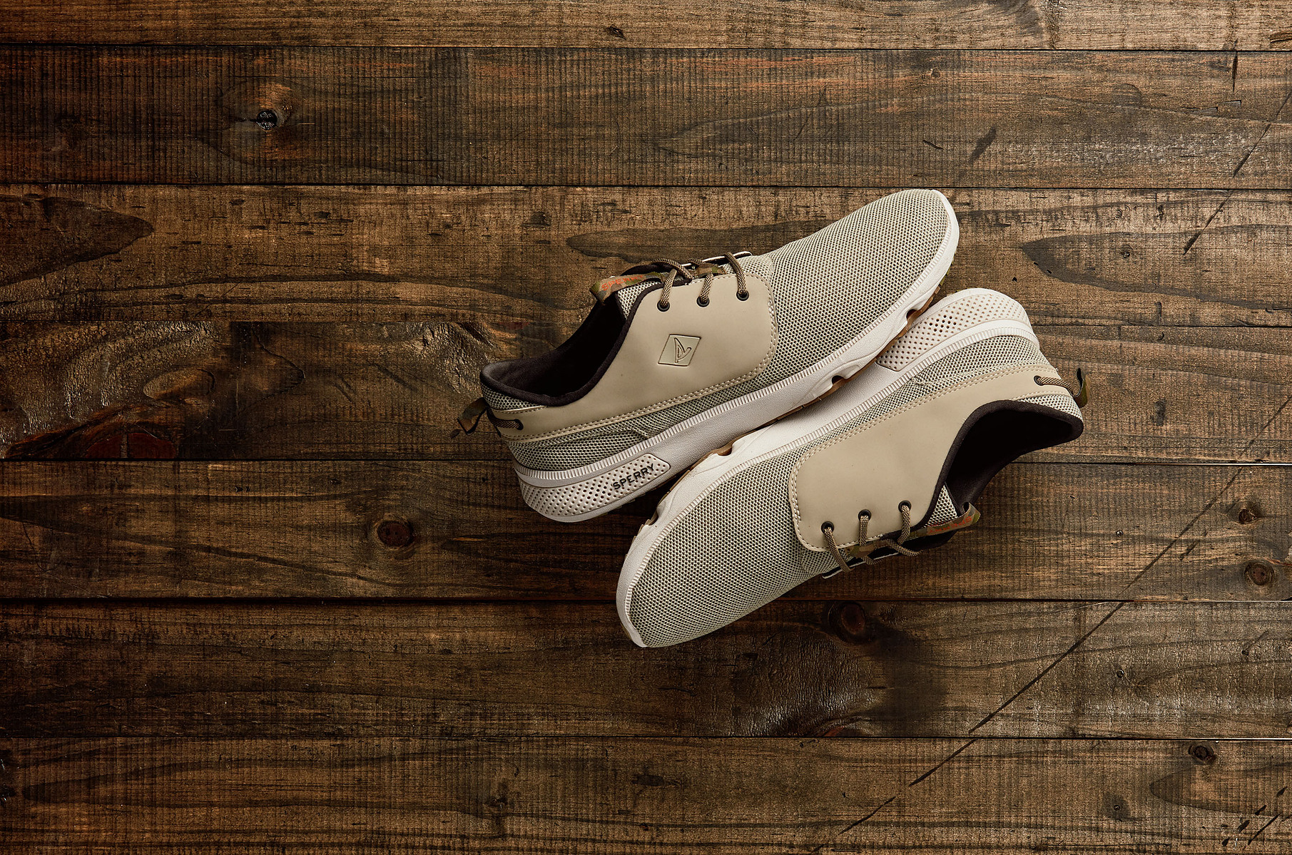 A pair of light-colored casual shoes photographed on a dark wooden surface.